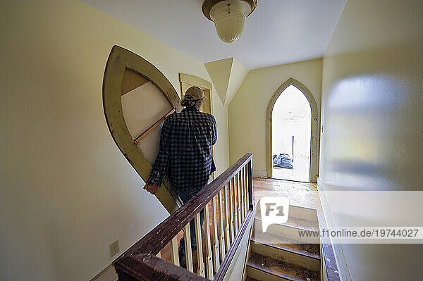 Carpenter installs a renovated door in a farmhouse; Dunbar  Nebraska  United States of America