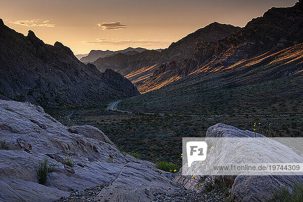 Sunrise illuminates the pass through the mountains at the western entrance to the Valley of Fire State Park  Nevada  United States of America  North America
