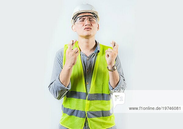 Porträt eines jungen Ingenieurs  der sich etwas wünscht. Hübscher Ingenieur kreuzt Finger und wünscht sich etwas
