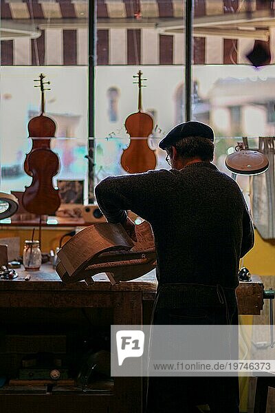 Senior Experte Geigenbauer Geigenbauer schnitzen Skulptur Meißel Rippen eines neuen klassischen Modells Cello in der Werkstatt Cremona Italien  selektiver Fokus  Bokeh