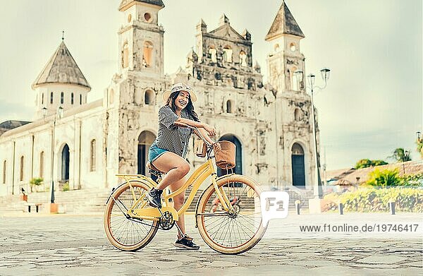 Glückliches Mädchen mit Hut fährt bei Sonnenuntergang Fahrrad. Tourismus und Reisen Konzept. Lifestyle eines glücklichen Mädchens mit Hut auf dem Fahrrad auf der Straße. Granada  Nicaragua  Mittelamerika