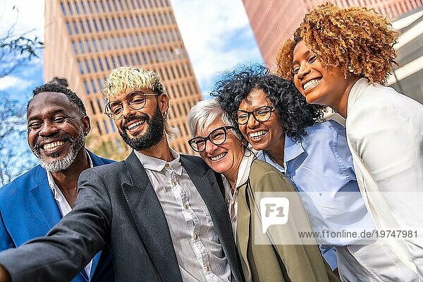 Niedriger Winkel Seitenansicht von multiethnischen Geschäftsleuten lächelnd und nehmen ein Selfie im Freien