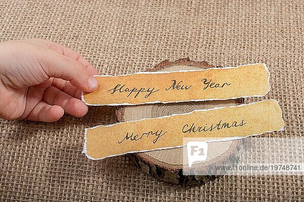 Frohes neues Jahr  Frohe Weihnachten  geschriebenes Papier auf Holz