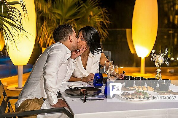 Romantische Szene eines Paares  das sich während des Abendessens auf einer luxuriösen Terrasse eines Restaurants küsst