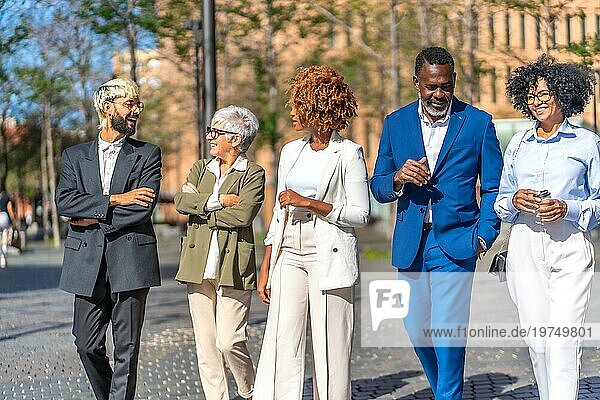 Elegante multikulturelle Geschäftsleute unterhalten sich entspannt bei einem Spaziergang durch die Stadt