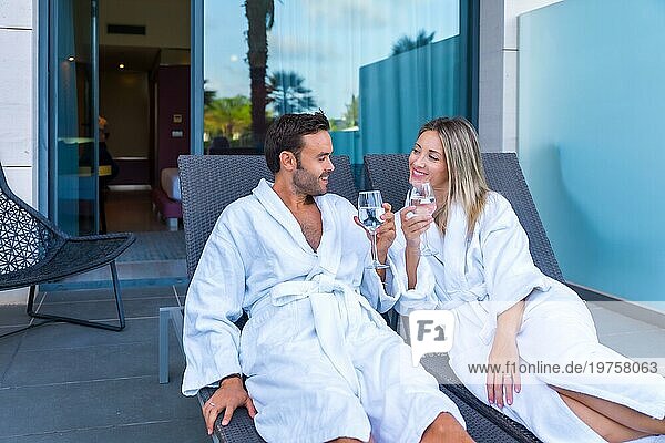 Ein glückliches Paar stößt mit Wein in einer Lounge im Freien in einem Luxus Spa an
