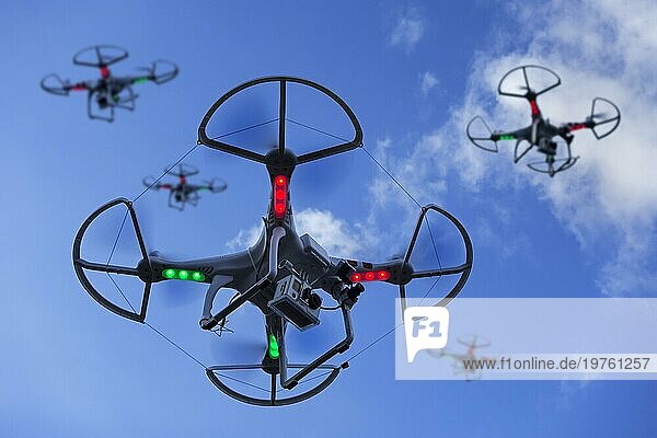 Gruppe von Miniatur Drohnen  unbemannte Luftfahrzeuge  UAV mit Kamera im Flug gegen blaün Himmel mit Wolken ausgestattet. MARKENNAMEN  LOGOS ENTFERNT