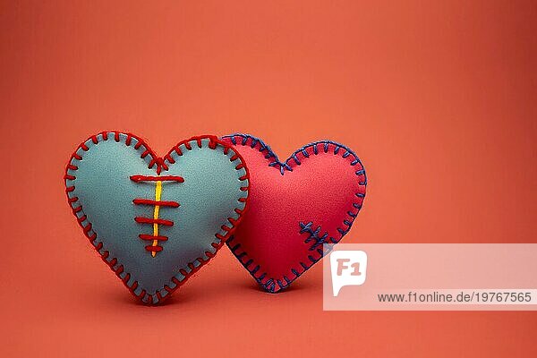 Hand genäht Schaumstoff Blatt blau und rosa Spielzeug Herzen über einen roten Hintergrund für romantische  Beziehung  Valentinstag  gebrochenes Herz Liebe Konzept