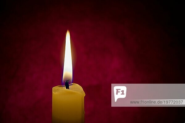 Einzelne rote Kerze brennt allein in der dunkelroten Hintergrund. Konzeptuelles Bild symbolisieren Frieden  Liebe  Hoffnung oder Geduld mit freiem Kopierraum
