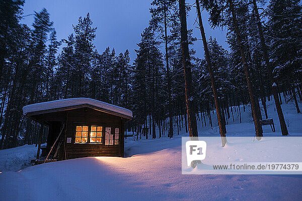 Log cabin with fire inside  winter  Lemmenjoki National Park  Finland  Europe