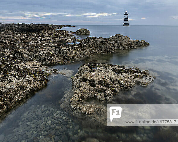 Rocks and Trwyn Du Lighthouse at dawn  Penmon Point  Anglesey  Wales  United Kingdom  Europe