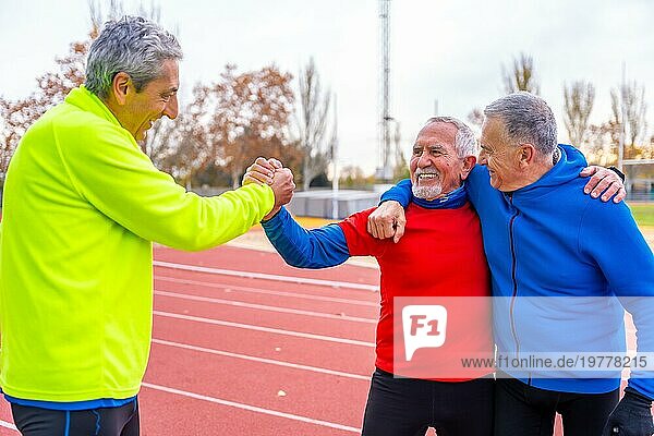 Glückliche ältere sportliche Männer  die zum Abschluss des Lauftrainings auf einer Outdoor Strecke gratulieren