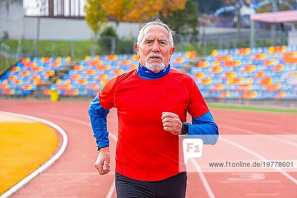 Porträt eines alten Mannes in Frontalansicht  der in einer Leichtathletikbahn läuft