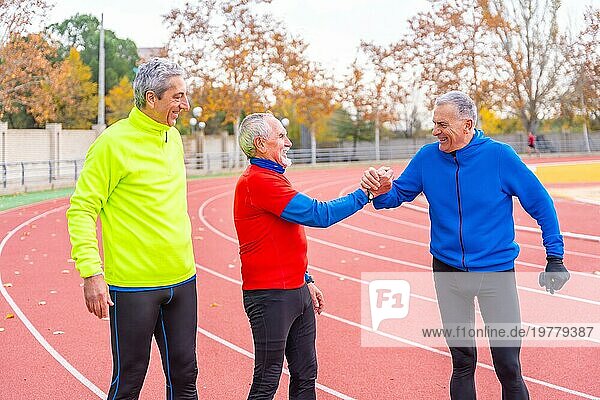 Glückliche ältere Freunde gratulieren zu einem schönen Lauftraining auf einer Outdoor Bahn