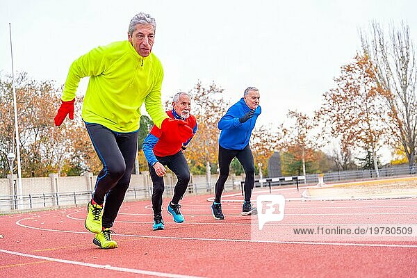 Ältere Menschen  die an einem kalten Wintertag auf einer Leichtathletikbahn im Freien laufen
