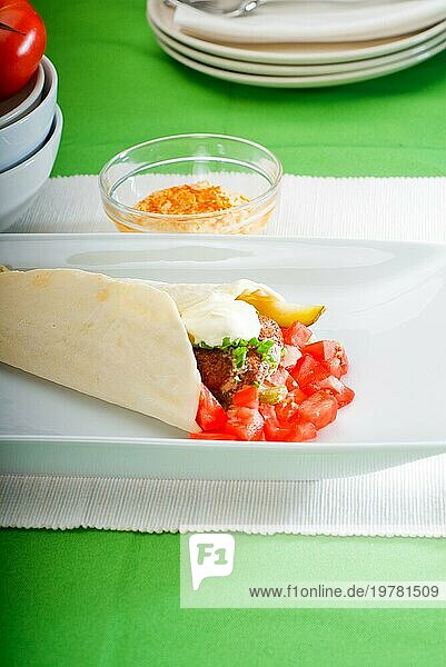 Frischer traditioneller Falafel Wrap auf Fladenbrot mit frischen gehackten Tomaten