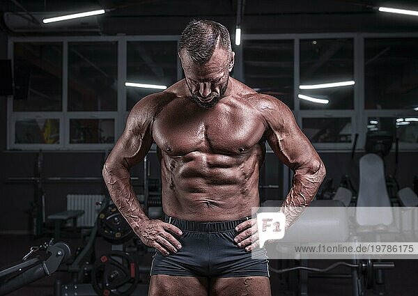 Bild eines starken Athleten  der im Fitnessstudio posiert. Fitness und Bodybuilding Konzept. Gemischte Medien