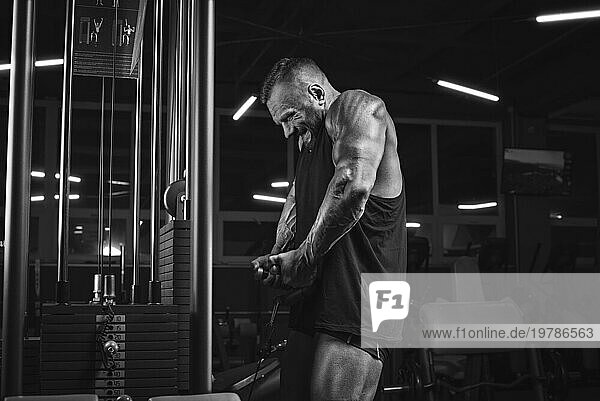 Bild eines kräftigen Sportlers  der im Fitnessstudio Gewichte hebt. Schultern pumpen. Fitness und Bodybuilding Konzept. Gemischte Medien