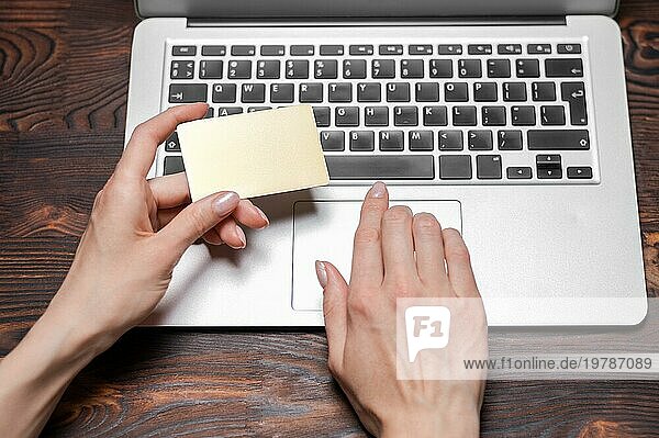 Bild von weiblichen Händen mit einer goldenen Bankkarte. Das Mädchen gibt die Kartennummer auf der Website ein. Konzept zum Einkaufen. Premium Konto. Gemischte Medien