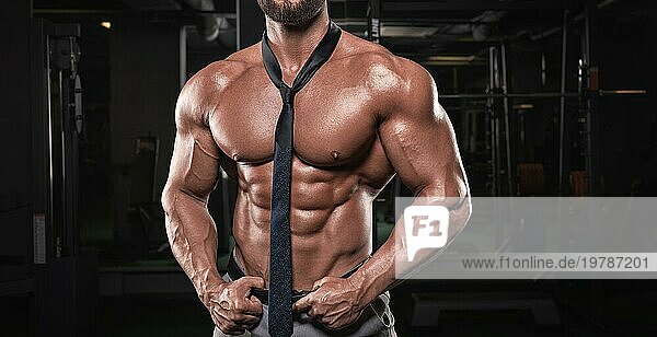 Attraktiver Männchen mit aufgepumptem Körper posiert im Fitnessstudio. Männliches Striptease Konzept. Gemischte Medien
