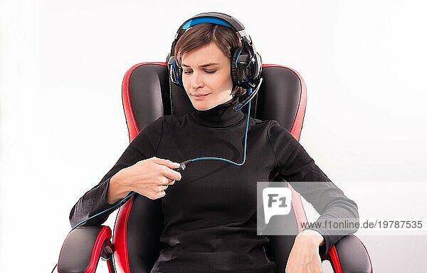 Porträt einer Frau  die in einem roten Gaming Stuhl sitzt und Kopfhörer trägt. Das Konzept der Spielsimulatoren und des E Sports. Gemischte Medien
