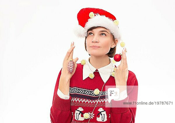 Bild einer schönen Frau in einem Weihnachtspulli  die sich etwas auf einem weißen Hintergrund wünscht. Feiertags Konzept. Gemischte Medien
