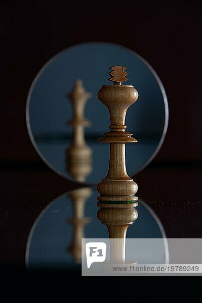 Spiegelung einer Dame-Schachfigur in einem Spiegel  davor mit scharfem Fokus eine König-Schachfigur  Schachfiguren  Symbolbild für Macht  Beziehung  Konflikte
