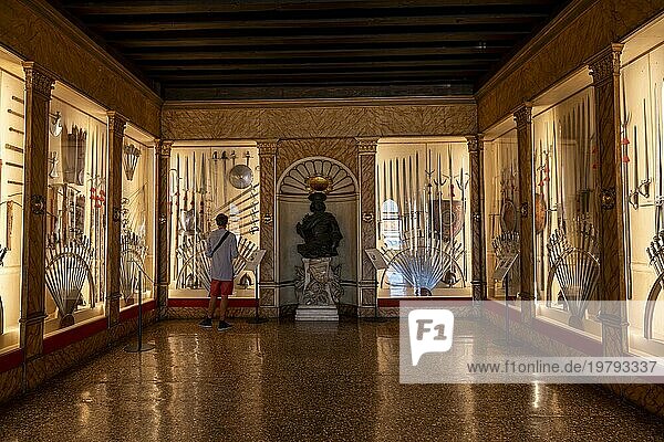Junger Mann in einem Ausstellungsraum mit mittelalterlichen Waffen  Schwerter und Schilde  Waffenkammer  Innenaufnahme  Dogenpalast  Palazzo Ducale  Venedig  Venetien  Italien  Europa