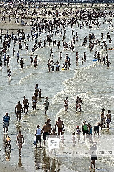 Touristen in Badeanzügen an einem überfüllten Strand beim Paddeln in der Nordsee an einem heißen Tag während der Sommerferien