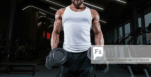 Hübscher junger Mann beim Training mit Hanteln im Fitnessstudio. Schultern pumpen. Fitness und Bodybuilding Konzept.