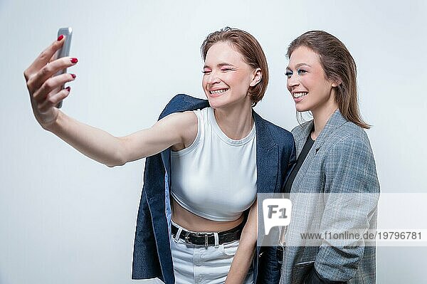 Porträt von zwei lachenden Frauen in Blazern  die ein Selfie machen. Konzept der Freundschaft.