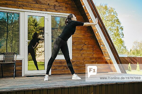 Attraktive sportliche Frau beim Workout auf der Terrasse eines Bungalows an einem sonnigen Tag