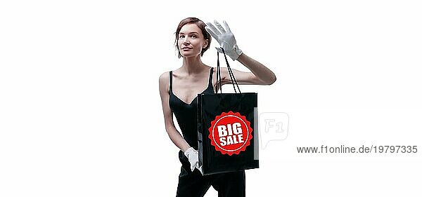 Schöne junge Frau in weißen Handschuhen hält eine schwarze Basteltasche in der Hand. Konzept der Shopaholics. Ausgeben. Geschenke für die Feiertage. Schwarzer Freitag. Einkaufszentren