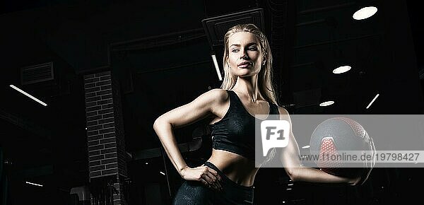 Charmante Blondine posiert im Fitnessstudio mit einem Fitnessball. Vorderansicht. Das Konzept von Sport  Bodybuilding  Fitness.