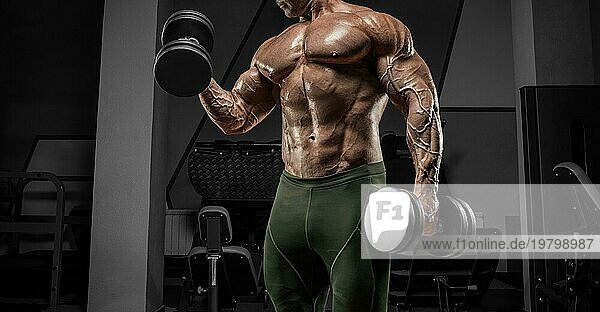 Kräftiger Bodybuilder trainiert in einem Fitnessstudio mit Hanteln. No name portrait. Bodybuilding Konzept.