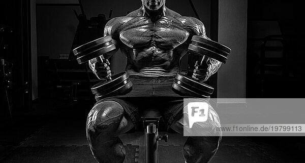 Muskulöser Mann sitzt auf einer Bank mit Hanteln. Bodybuilding und Kraftdreikampf Konzept.