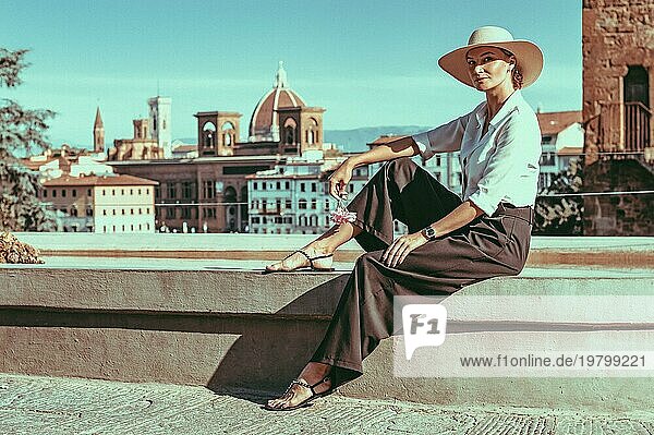 Porträt eines reizenden Mädchens  das in der Nähe eines Brunnens in Florenz sitzt. Ansicht von Santa Maria del Fiore. Tourismus Konzept. Italien. Gemischte Medien