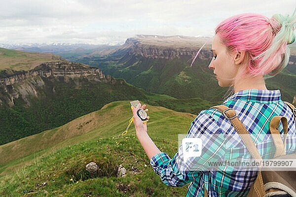 Ein Hipster Mädchen reiste mit einem Blogger in einem karierten Hemd und mit bunten Haaren mit einem Kompass im Hintergrund in den Hintergrund der kaukasischen Landschaft mit einem Plateau