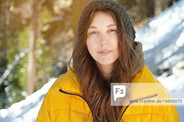 Schöne freundliche kaukasische junge Frau in Winterkleidung lächelnd niedlich Blick in die Kamera in einem Winterwald durch Schnee umgeben