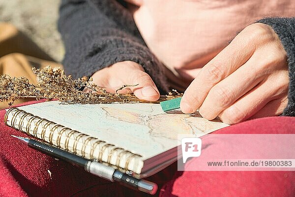 Nahaufnahme einer Hand Mädchen Künstler malt ein Pastell in einem Notizbuch auf die Natur in den Bergen. Freie Kreativität und Freiberuflichkeit