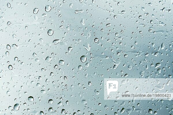 Texturierter Hintergrund von Fensterscheiben mit bewölktem Hintergrund. Natürliches Muster aus einem Regentropfen auf einem bewölkten Hintergrund