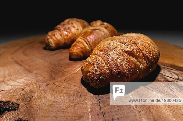 Drei frisch gebackene Croissants auf einem Holztablett. Leckeres und gesundes Frühstück