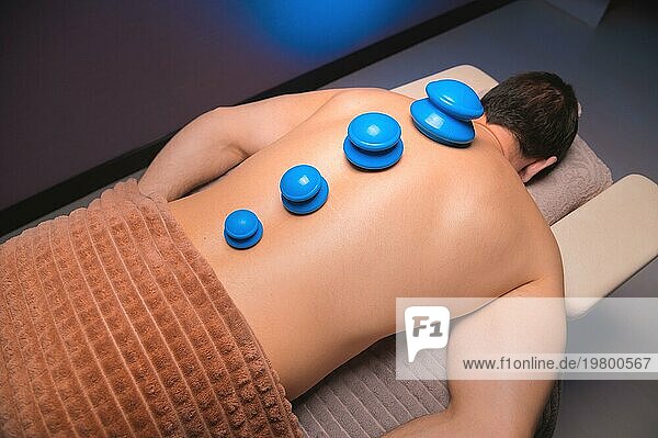 Vakuum Gummisauger für Schröpftherapie auf dem Rücken eines nackten Mannes. Massage im Spa  medizinische Behandlung für den Rücken. Revitalisierende und entspannende Massage  Fitnessbehandlungen