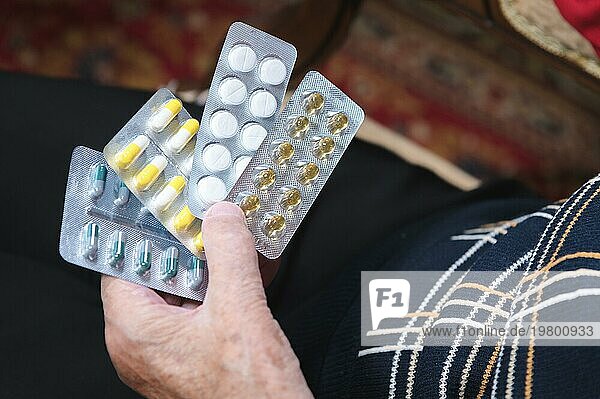 Verschiedene Pillen in den Händen einer alten Frau. Das Konzept der Probleme bei der Auswahl von Medikamenten für alte Menschen und deren Kosten