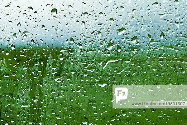 Natürlicher Hintergrund Tropfen auf beiden Seiten des Glases vom Regen und vom Beschlagen abstrakte Ansicht  Regentropfen gegen das blaue Glas und die verschwommene Landschaft des Farbverlaufs von Blau und Grün