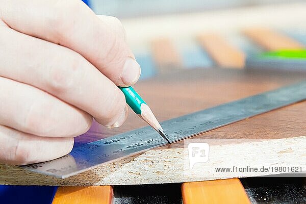 Die Nahaufnahme der Hand des Tischlermeisters ist mit einem Lineal und einem Bleistiftrohling markiert. Das Konzept der manuellen Möbelproduktion