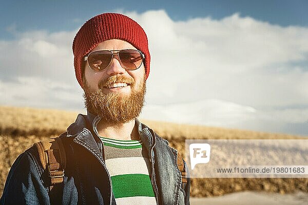 Porträt eines jungen Hipster Mannes mit Sonnenbrille und Hut. Ein lächelnder  bärtiger Mann mit Sonnenbrille. Glücklicher Mann mit Bart