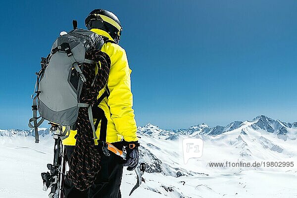 Ein Bergsteiger hält einen Eispickel hoch in den schneebedeckten Bergen. Blick von hinten. outdoor extrem outdoor klettern sport mit Bergsteigerausrüstung