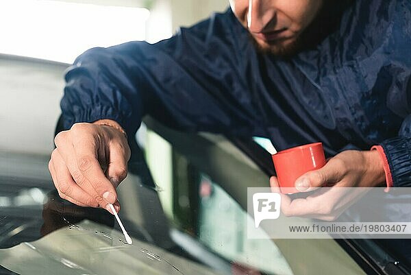 Close up Autoglaser Arbeiter Befestigung und Reparatur Windschutzscheibe oder Windschutzscheibe eines Autos in Auto Service Station Garage