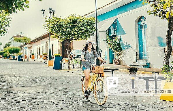 Schönes und glückliches Mädchen beim Fahrradfahren auf der Straße von La Calzada  Granada  Nicaragua. Tourist Frau fährt ein Fahrrad auf den Straßen von Granada